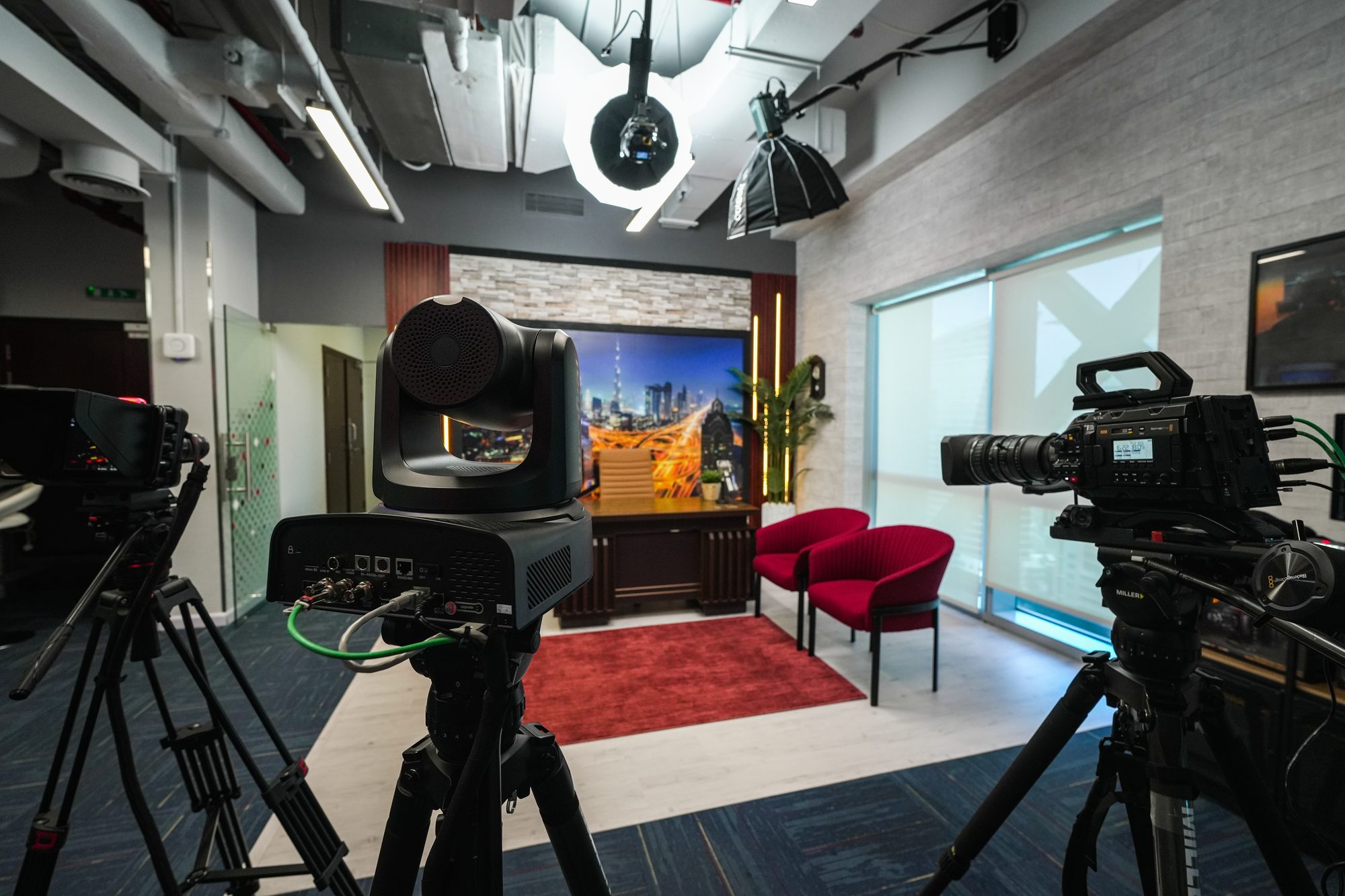 Two studio cameras rigged on the MCX set, the city backdrop lit behind them